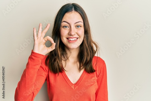 Young brunette woman wearing casual clothes smiling positive doing ok sign with hand and fingers. successful expression.