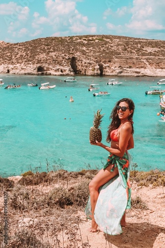 Smiling Hispanic woman holding pineapple fruit standing on seashore photo