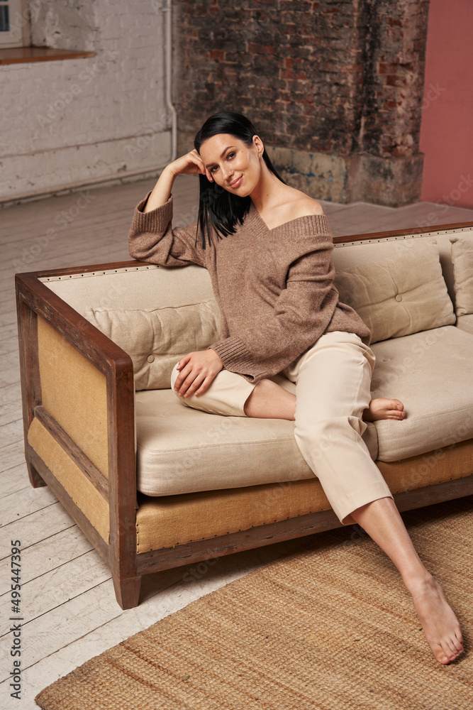 young woman sitting on a cozy sofa in a large room young woman sitting on a cozy sofa in a large room