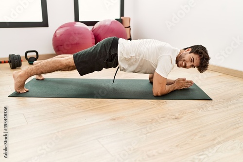 Young hispanic man smiling confident training abs exercise at sport center