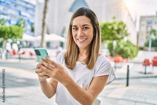 Free Download Young hispanic woman smiling confident using smartphone at street - GFXLoad
