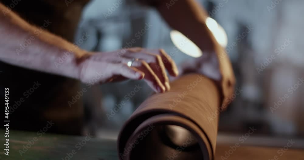 Craftsman unrolling leather on workbench