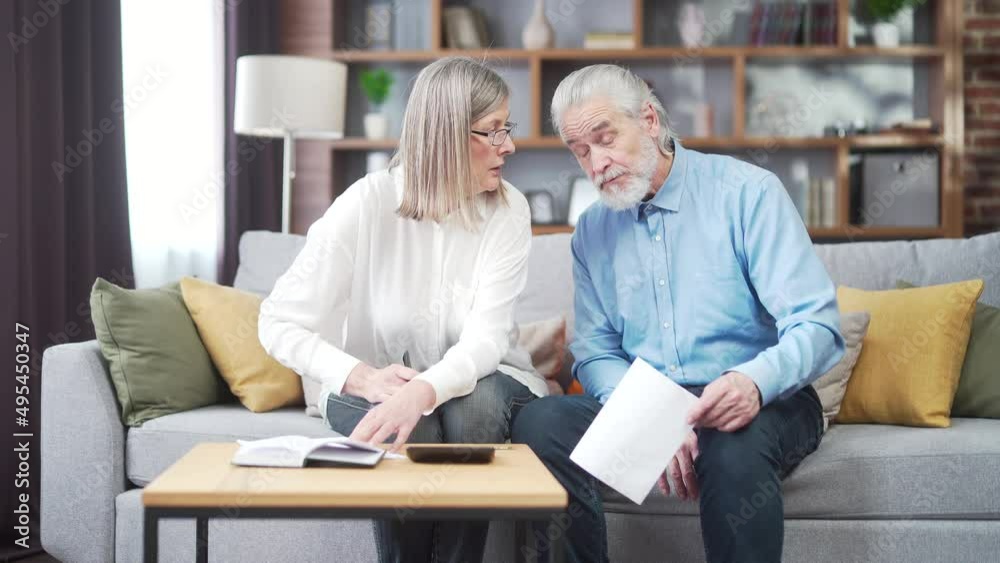 gray hair mature senior couple counting money and calculating finances while preparing tax report at home Older family with payment domestic bill checking financial documents, planning budget together