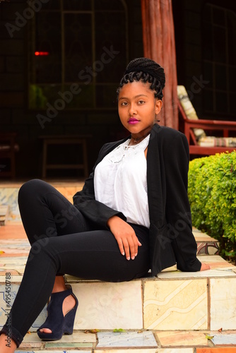 Young woman in dark blazer and pants sitting on doorstep photo