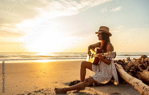 Fototapet Sunset over ocean with Indian girl playing guitar