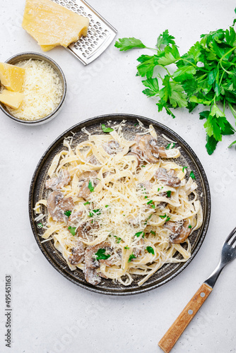 Mushroom Tagliatelle Pasta with parmesan cheese and cream sauce on white background, top view. Prepared italian pasta with champignon on gray plate