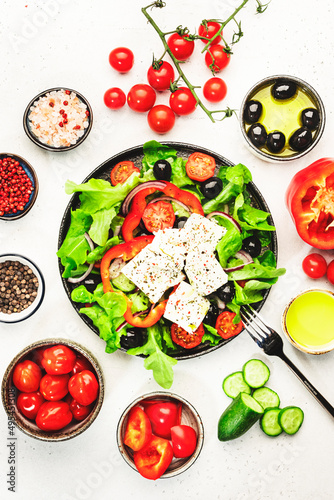 Greek salad with feta cheese, olives, cherry tomato, paprika, cucumber and red onion, healthy vegeterian mediterranean diet food, low calories eating. White stone background, top view
