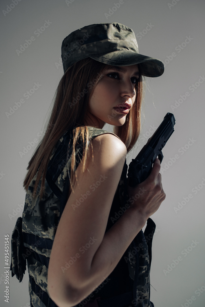 Portrait of young woman in uniform with handgun in her hand.