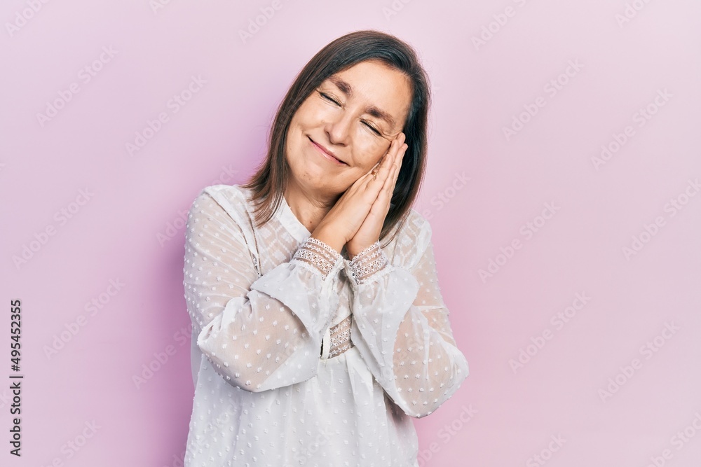 Middle age hispanic woman wearing casual clothes sleeping tired dreaming and posing with hands together while smiling with closed eyes. Middle age hispanic woman wearing casual clothes sleeping tired dreaming and posing with hands together while smiling with closed eyes.
