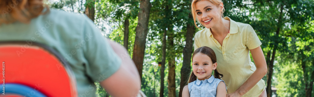 happy mother and daughter looking at boy on blurred foreground, banner. happy mother and daughter looking at boy on blurred foreground, banner.