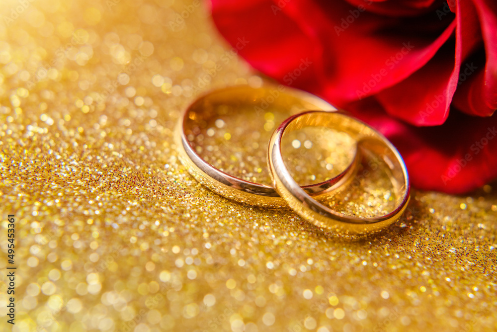 Gold wedding rings and Red roses on a Golden background
Gold wedding rings and Red roses on a Golden background