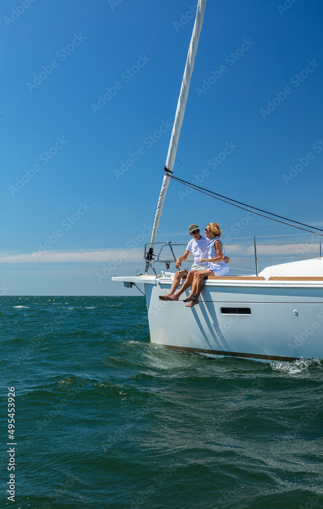 Senior couple enjoying retirement sailing yacht across ocean