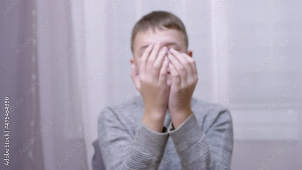 Cheerful Smiling Caucasian Boy Blowing a Kiss While Stretching his Hand Forward. A happy child waves hands goodbye, hello, bye, gesticulates with palms and fingers. A teenager sits in a chair in room. Cheerful Smiling Caucasian Boy Blowing a Kiss While Stretching his Hand Forward. A happy child waves hands goodbye, hello, bye, gesticulates with palms and fingers. A teenager sits in a chair in room.