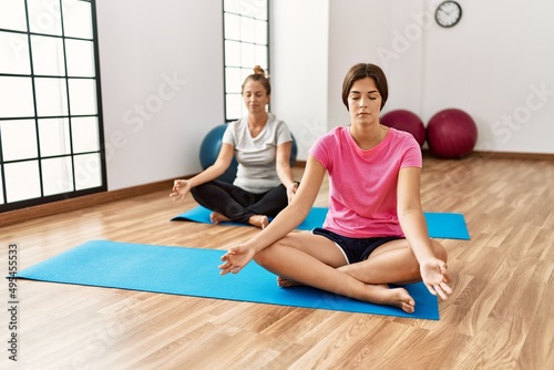 Mother and daughter training yoga at sport center
