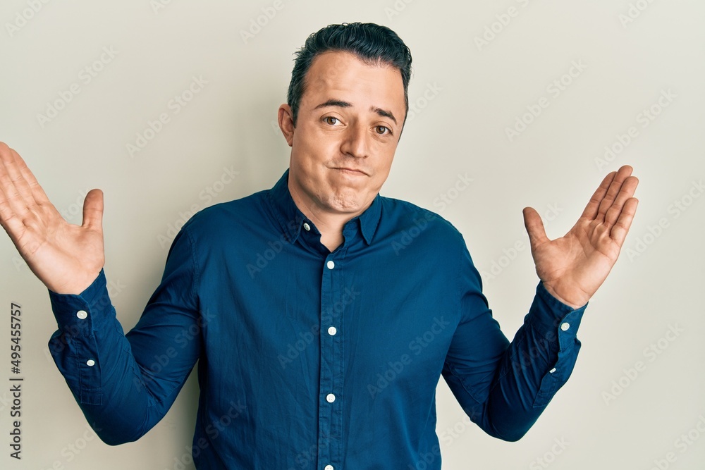 Fototapeta premium Handsome young man wearing business shirt clueless and confused with open arms, no idea and doubtful face.