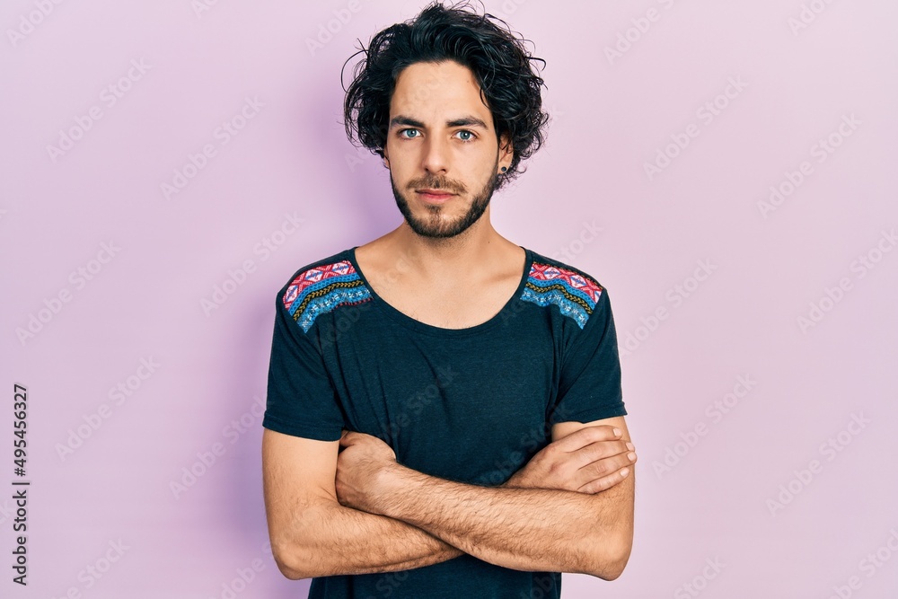 Handsome hispanic man with arms crossed gesture relaxed with serious expression on face. simple and natural looking at the camera.