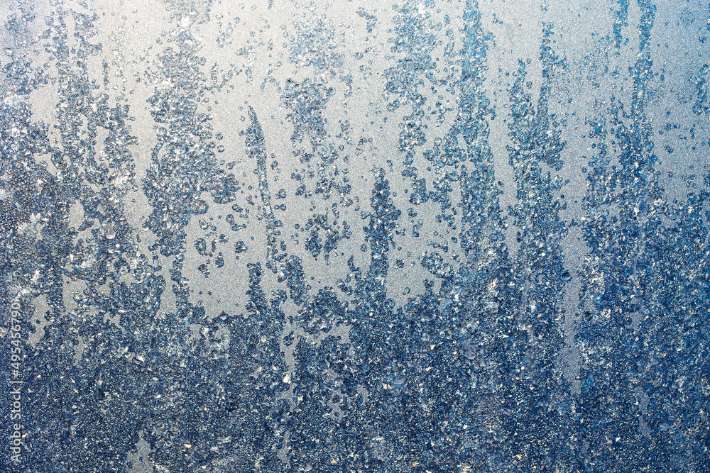 The texture of ice crystals and frozen water droplets on the window. Winter silver-blue background The texture of ice crystals and frozen water droplets on the window. Winter silver-blue background