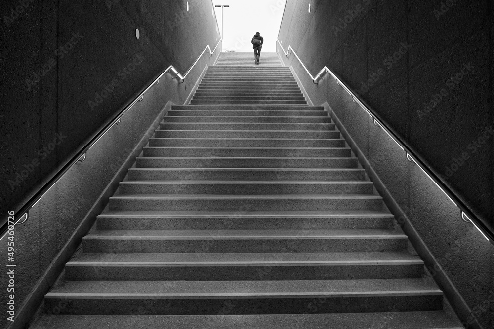 Rear view of an unrecognizable man walking up subway stairs into the light Rear view of an unrecognizable man walking up subway stairs into the light