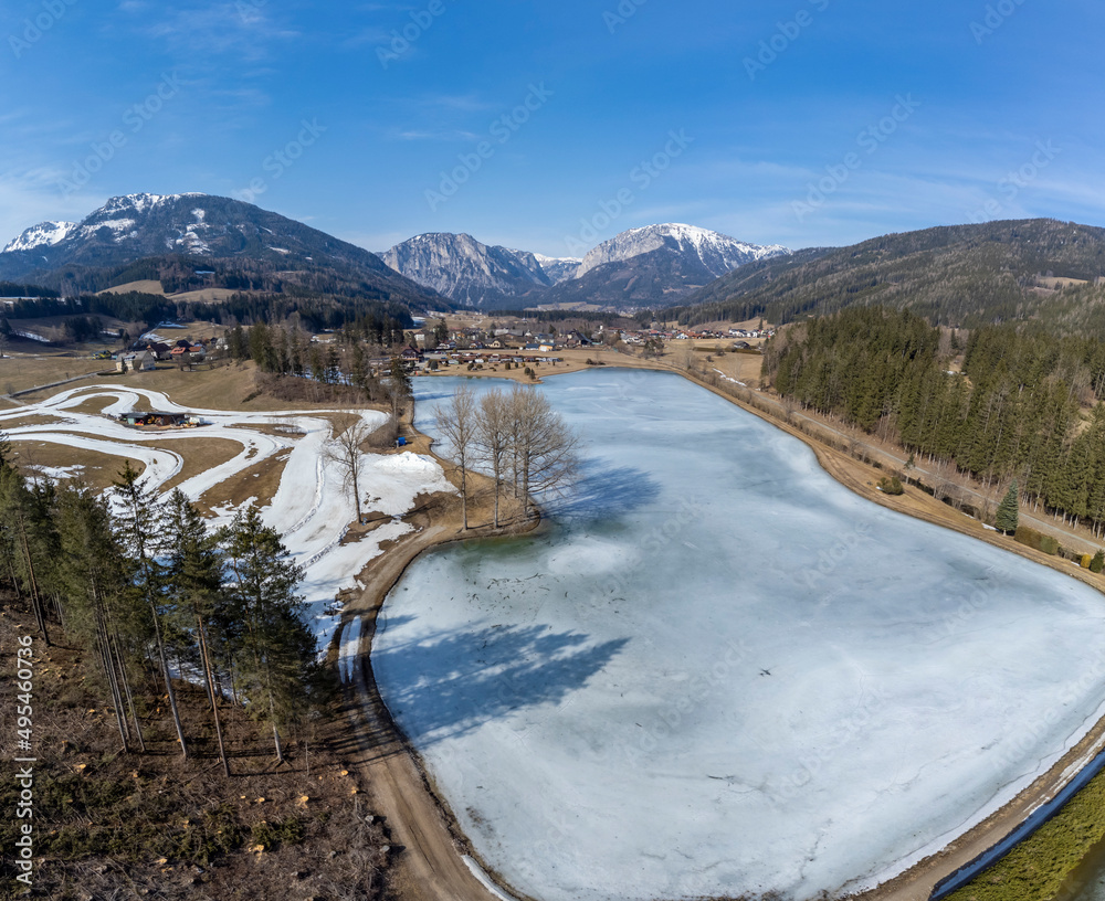 aerial view frozen lake Zenzsee in Styria, Austria.In the background mountain range Hochschwab with peaks Pribitz and Messnerin