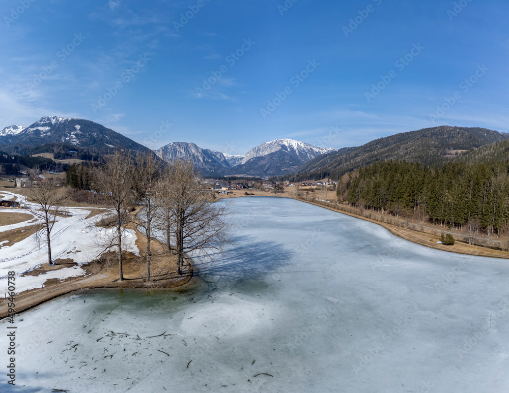 aerial view frozen lake Zenzsee in Styria, Austria.In the background mountain range Hochschwab with peaks Pribitz and Messnerin