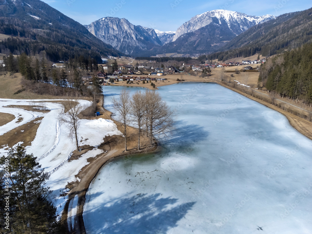 aerial view frozen lake Zenzsee in Styria, Austria.In the background mountain range Hochschwab with peaks Pribitz and Messnerin