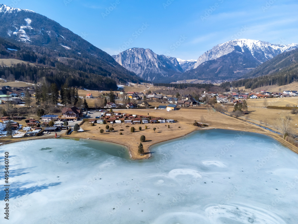 aerial view frozen lake Zenzsee in Styria, Austria.In the background mountain range Hochschwab with peaks Pribitz and Messnerin