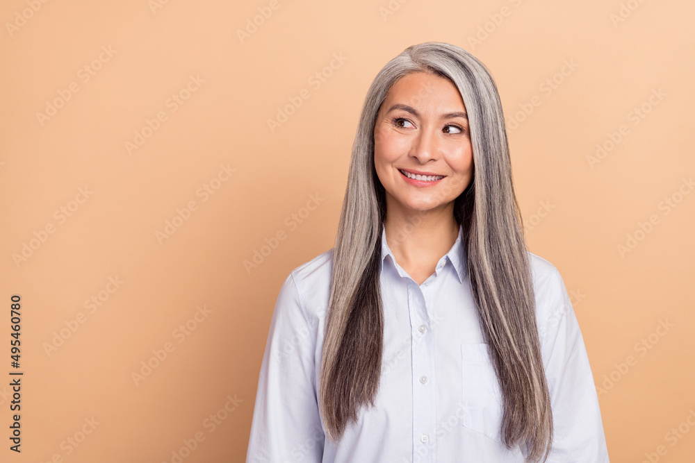 Photo of mature lady curious look empty space think plan smart leader isolated over beige color background