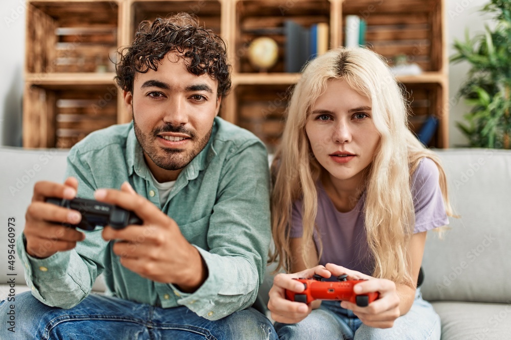 Young couple smiling happy playing video game at home. Young couple smiling happy playing video game at home.