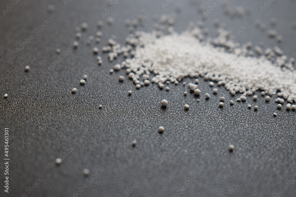 Small round granules on a black background. Laundry bleaching powder in granules. Small round granules on a black background. Laundry bleaching powder in granules.