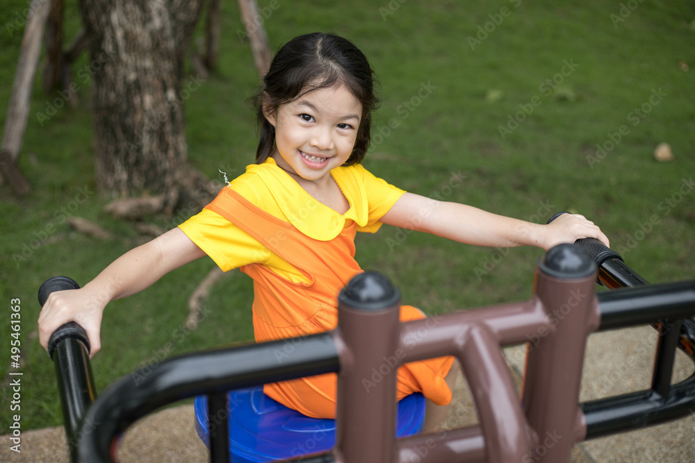 Obraz premium Asian happy girl with orange dress is playing in the playground.