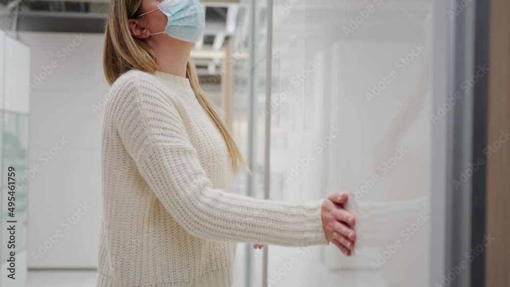 a young woman in a protective mask in a furniture store chooses a tall wardrobe with pitched doors, taking out storage containers from it and inspecting them a young woman in a protective mask in a furniture store chooses a tall wardrobe with pitched doors, taking out storage containers from it and inspecting them
