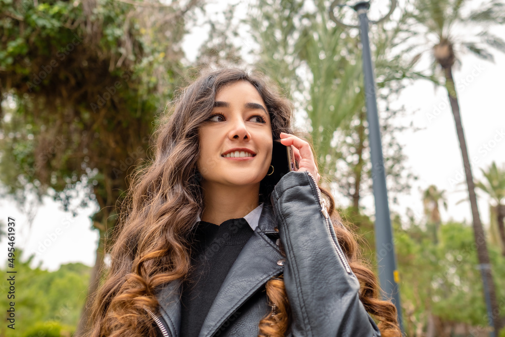 Young smiling woman talking on the phone, beautiful woman with wavy hair is having a job interview, a lady smiling and talking on the phone