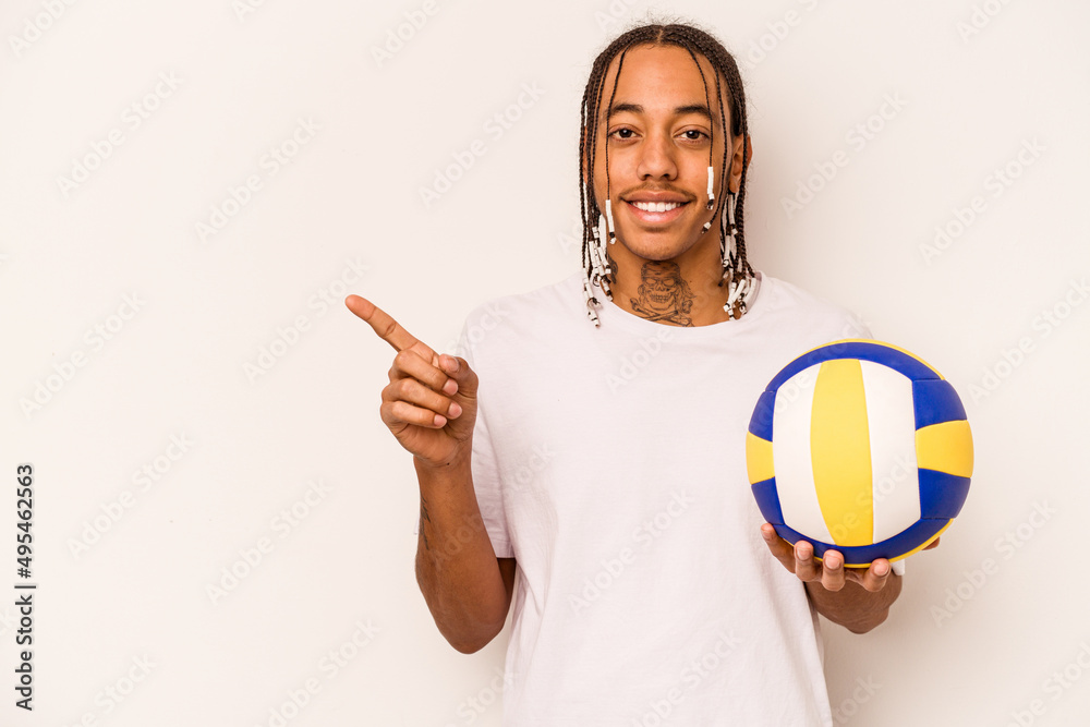 Young African American man playing volleyball isolated on white background smiling and pointing aside, showing something at blank space.