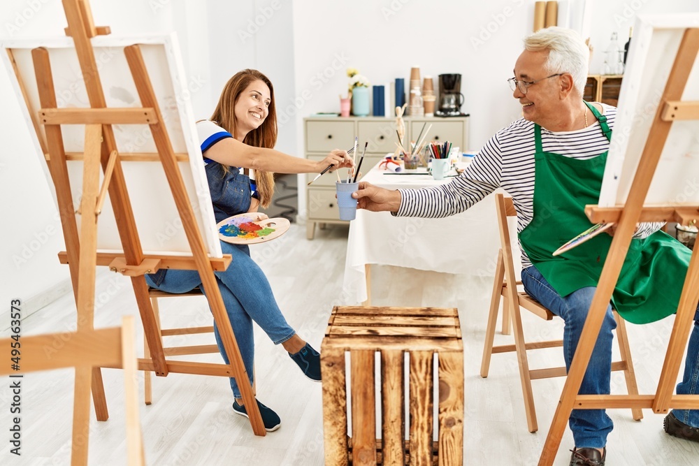 Two middle age artists smiling happy painting at art studio.