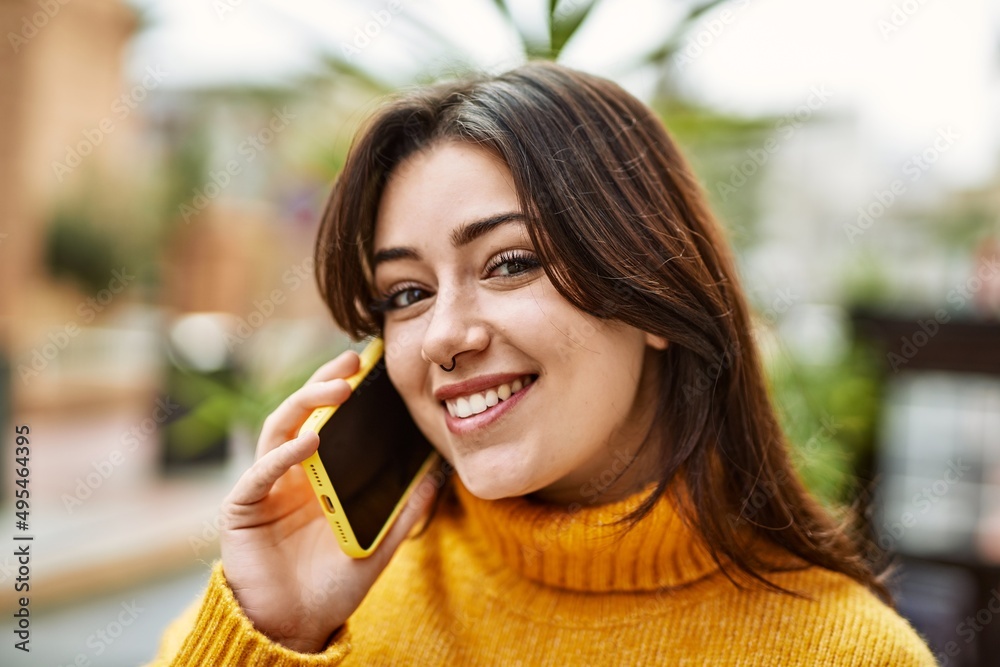 Young beautiful brunette woman wearing turtleneck sweater outdoors speaking on the phone