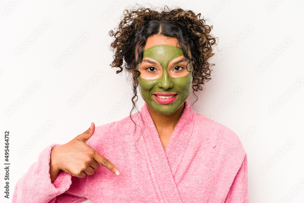 Young hispanic woman wearing a facial mask isolated on white background person pointing by hand to a shirt copy space, proud and confident