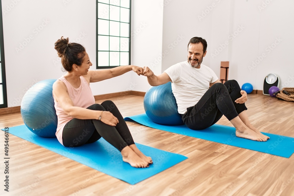 Mature hispanic couple doing excersice and stretching at yoga room. Two adult people doing pilates and flexibility workout Mature hispanic couple doing excersice and stretching at yoga room. Two adult people doing pilates and flexibility workout
