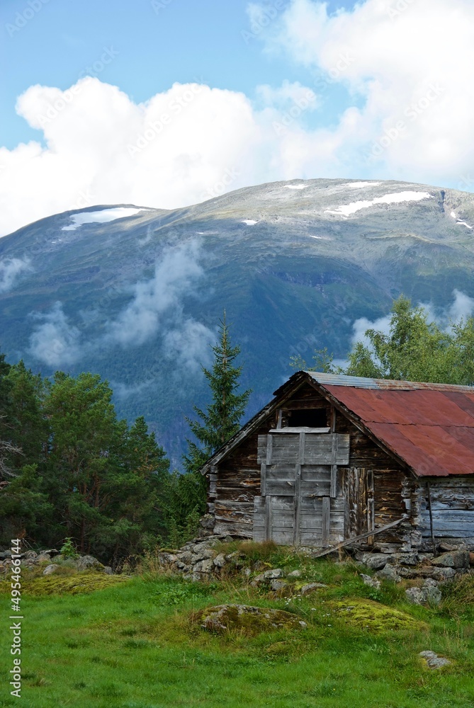Old and worn wooden cottage in a forest glade in a mountainous landscape in Sogn og Fjordane fylke in Norway.