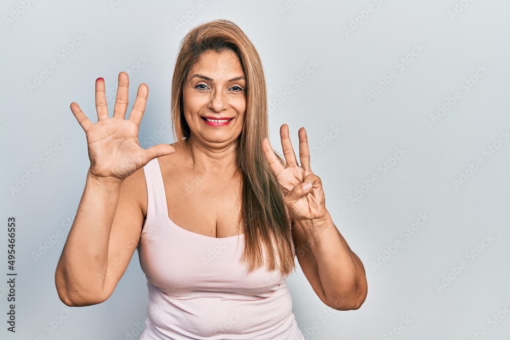 Fototapeta premium Middle age hispanic woman wearing casual style with sleeveless shirt showing and pointing up with fingers number eight while smiling confident and happy.