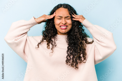 Young hispanic woman isolated on blue background touching temples and having headache.
