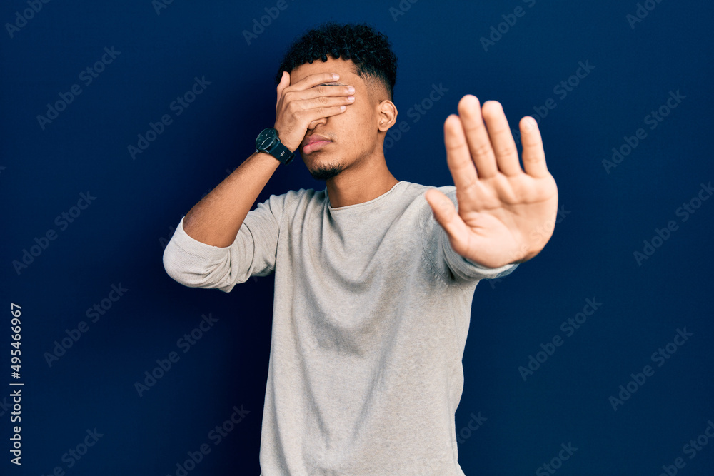 Young african american man wearing casual clothes covering eyes with hands and doing stop gesture with sad and fear expression. embarrassed and negative concept. Young african american man wearing casual clothes covering eyes with hands and doing stop gesture with sad and fear expression. embarrassed and negative concept.