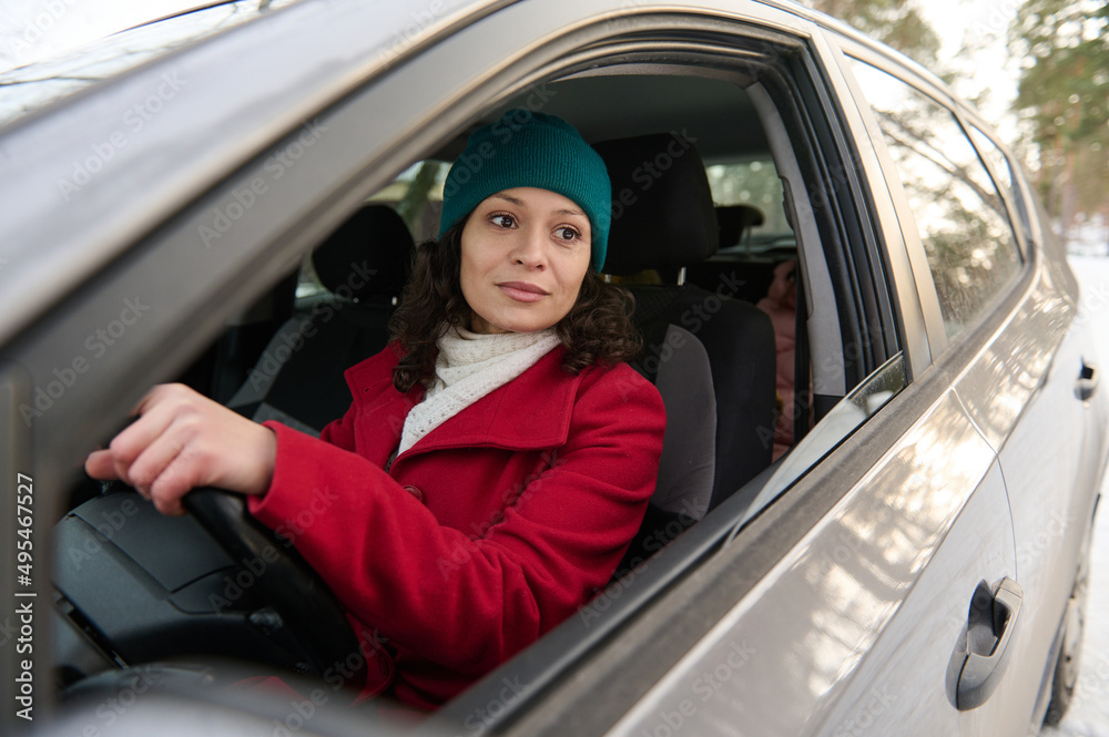 Confident charming middle-aged woman driving a car. Charming successful woman sits in the driver's seat of a car and drives confidently on a snowy road, traveling in winter Confident charming middle-aged woman driving a car. Charming successful woman sits in the driver's seat of a car and drives confidently on a snowy road, traveling in winter
