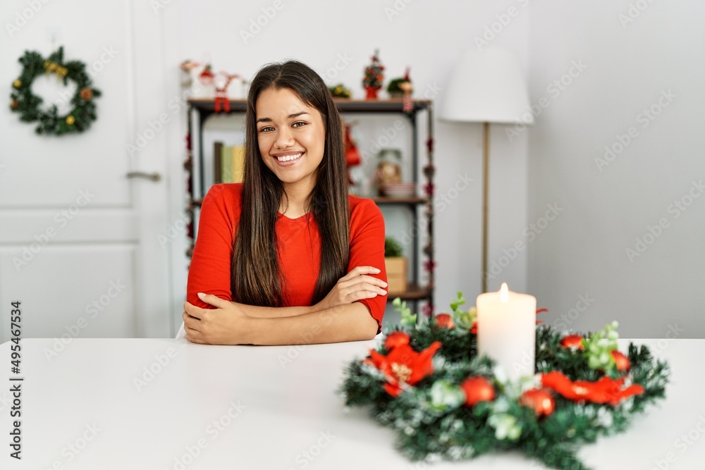 Young brunette woman sitting on the table on christmas happy face smiling with crossed arms looking at the camera. positive person. Young brunette woman sitting on the table on christmas happy face smiling with crossed arms looking at the camera. positive person.