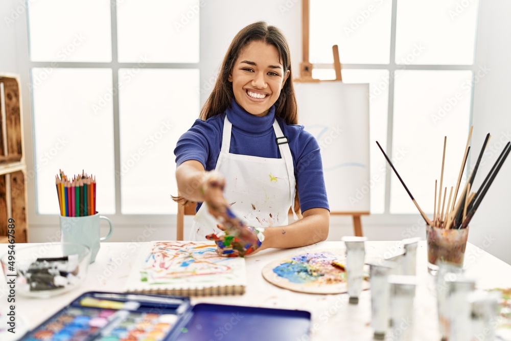 Young brunette woman at art studio with painted hands smiling friendly offering handshake as greeting and welcoming. successful business. Young brunette woman at art studio with painted hands smiling friendly offering handshake as greeting and welcoming. successful business.