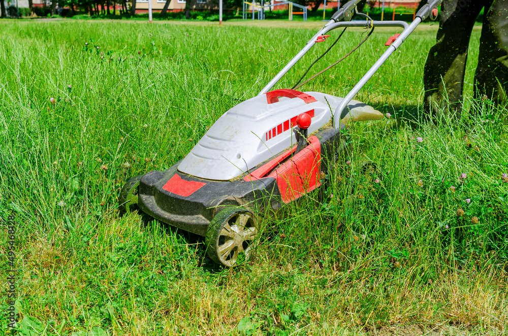 A man mows the grass with an electric lawn mower. Freshly mown grass. A man mows the grass with an electric lawn mower. Freshly mown grass.