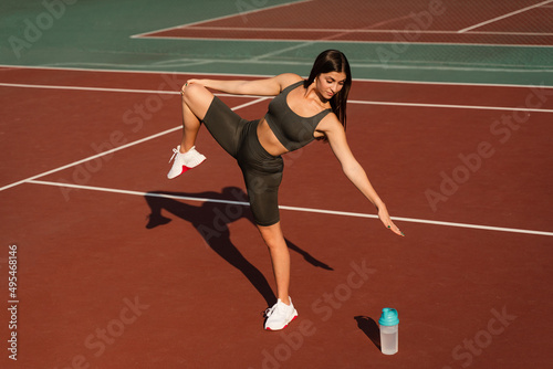 Warm-up and stretching before street workout. Attractive asian girl training on the tennis court.