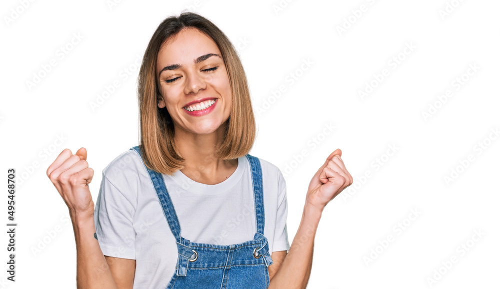 Young blonde girl wearing casual clothes very happy and excited doing winner gesture with arms raised, smiling and screaming for success. celebration concept. Young blonde girl wearing casual clothes very happy and excited doing winner gesture with arms raised, smiling and screaming for success. celebration concept.