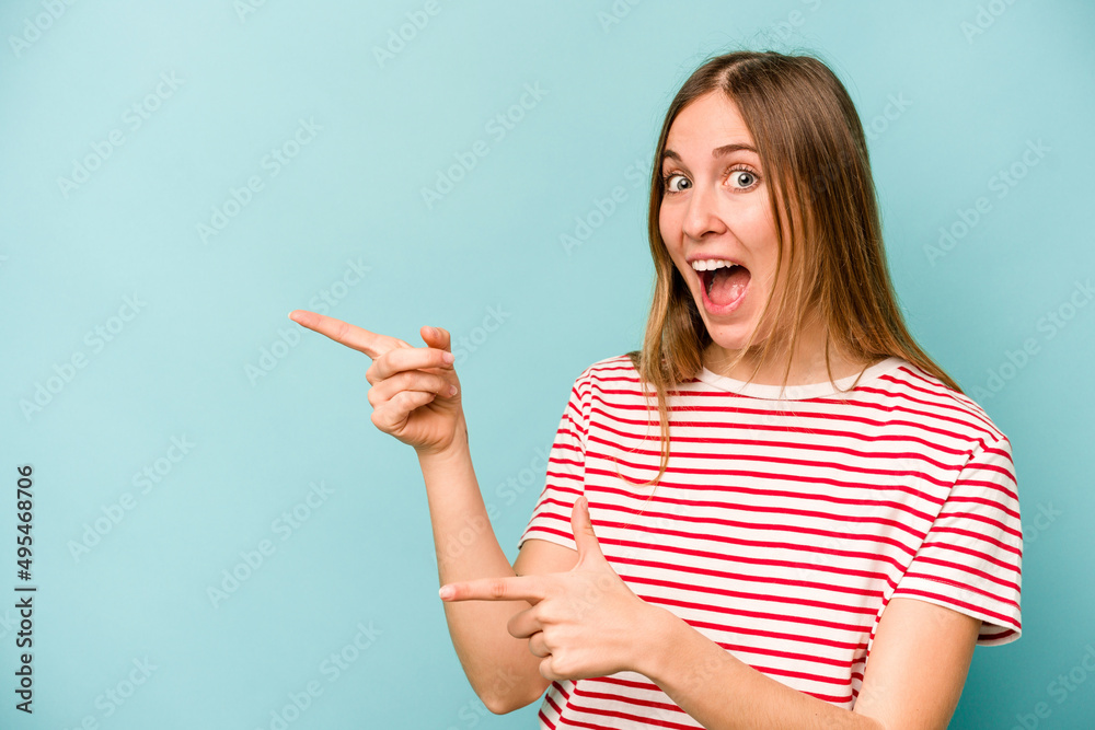 Young caucasian woman isolated on blue background excited pointing with forefingers away. Young caucasian woman isolated on blue background excited pointing with forefingers away.