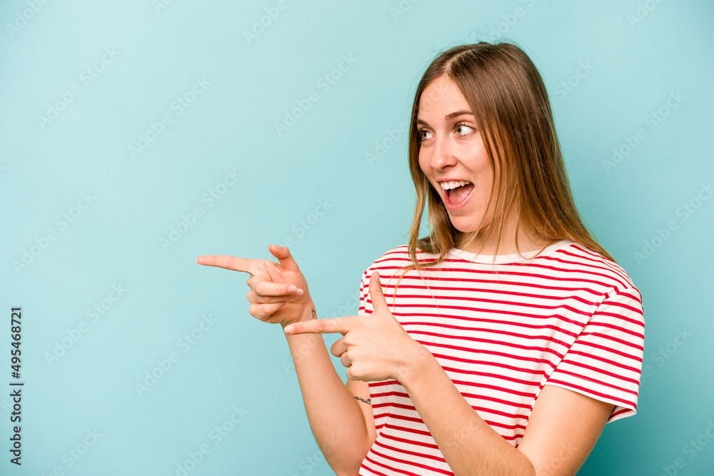 Young caucasian woman isolated on blue background points with thumb finger away, laughing and carefree. Young caucasian woman isolated on blue background points with thumb finger away, laughing and carefree.