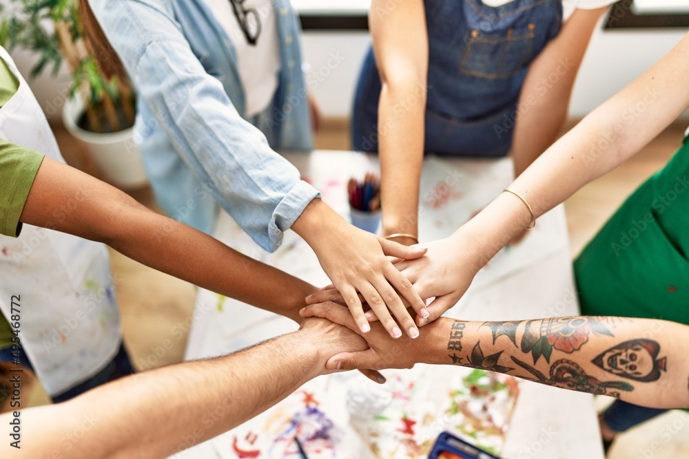 Group of people standing with united hands at art studio.